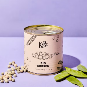Eine Dose mit Bio-Erbsen vor einem blauen Hintergrund. Davor dekoriert sind Hülsenfrüchte und getrocknete Erbsen