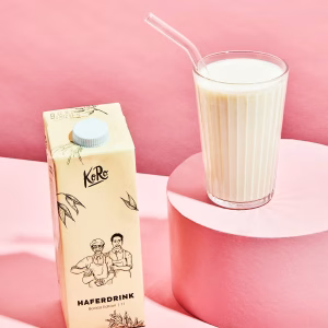 Ein Karton Milch und ein Glas Milch stehen nebeneinander auf einer Oberfläche.