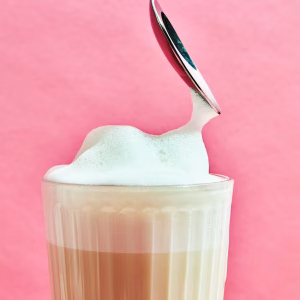 Ein Löffel wird in eine Tasse mit Latte eingetaucht