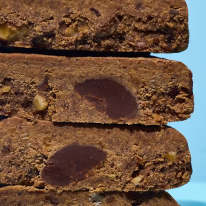 vier Stück offene Proteinriegel liegen aufgeschnitten übereinander vor blauem Hintergrund