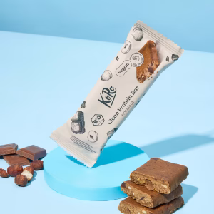 Eine Packung Proteinriegel vegan und drei Stücke des Riegels liegen offen vor blauem Hintergrund